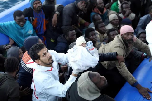 A migrant baby is carried as other migrants in a dingy are rescued by Libyan coast guards off the coast of Garabulli, east of Tripoli, Libya, January 8, 2018