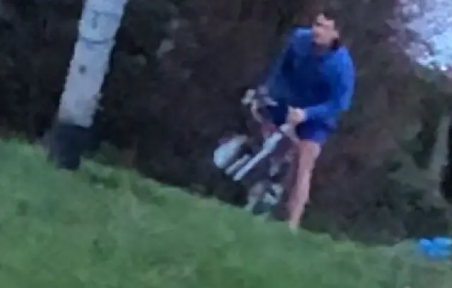 A man on a bike with a blue coat.