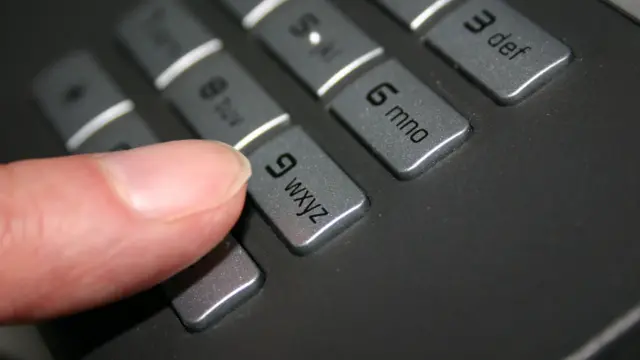 Finger poised to dial 9 on a phone