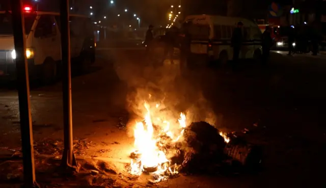 Police vehicles stop in front of burning tires set up by protesters during demonstrations against rising prices and tax increases, in Tunis, Tunisia, January 8, 2018