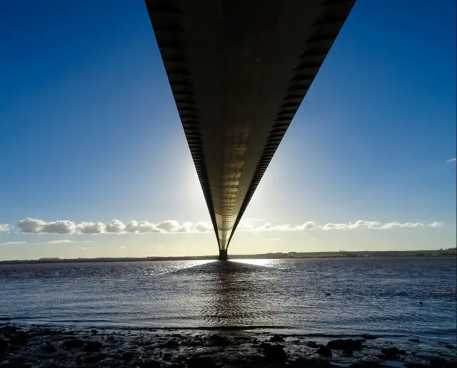 The Humber Bridge from below, looking across the river Humber.