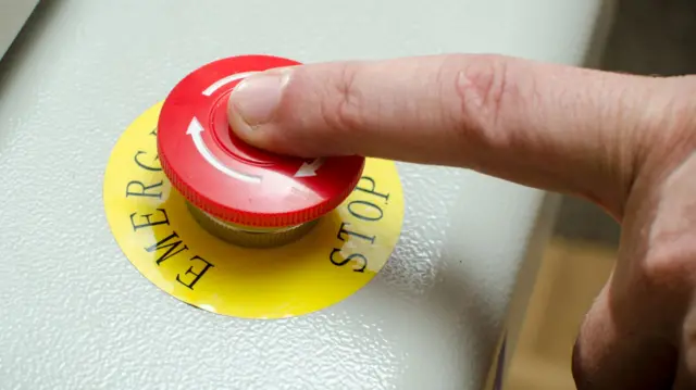 A finger on an emergency stop button