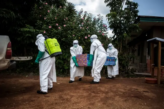 Ebola health workers carrying a coffin