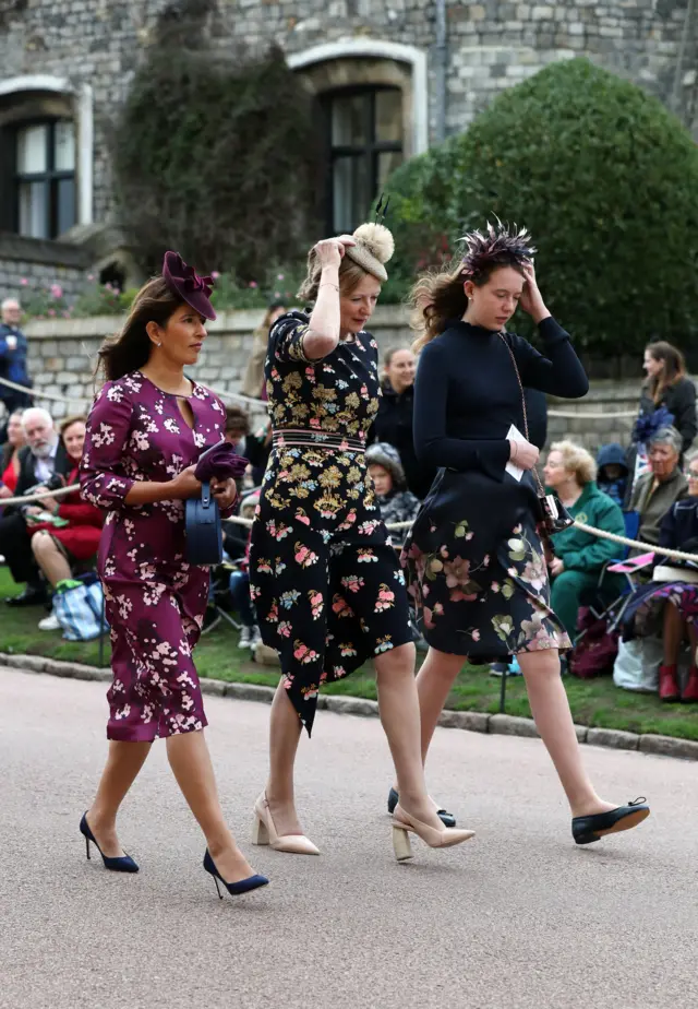 Guests holding onto their hats as they arrive for the wedding