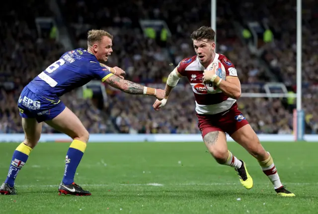 Wigan Warriors' Oliver Gildart (right) goes past Warrington Wolves' Kevin Brown