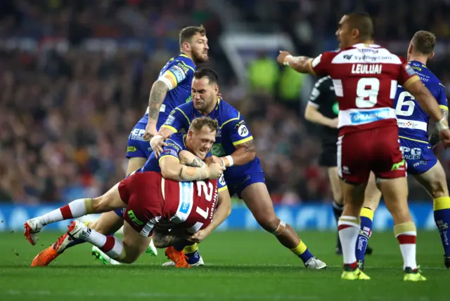 Dom Manfredi of Wigan Warriors is tackled