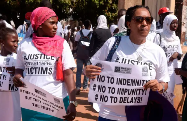 Demonstrators hold placards reading 'They killed our children but they can't kill the truth' and 'No to indemnity, no to impunity, no to delays' during a march in rememberance of victims of The Gambia's former regime, in Serekunda, on April 10, 2017