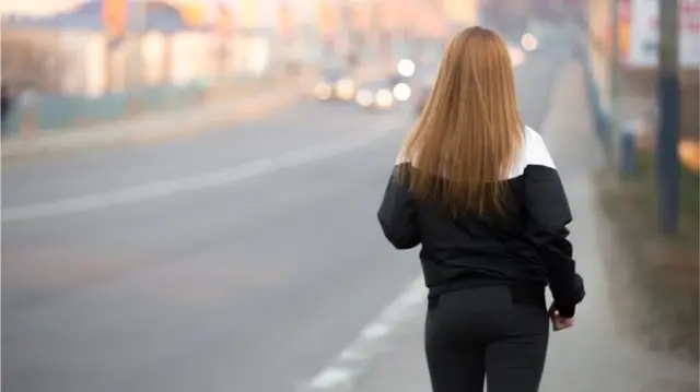 A young person walks down a road