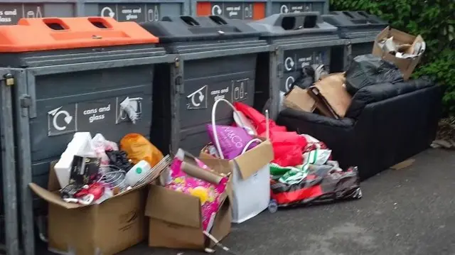 Rubbish, including sofa, dumped alongside recycling bins