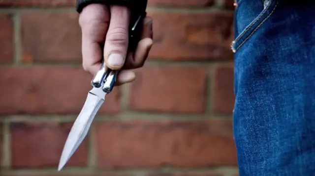 A close up of a person holding a flick knife