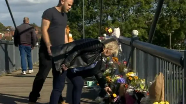 People putting tributes on the bridge