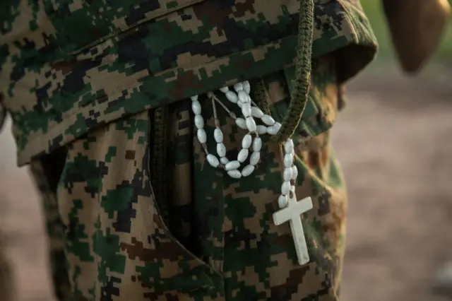 A rebel of the Sudan People's Liberation Movement-in-Opposition (SPLM-IO), a South Sudanese anti-government force, stands with a rosary hanging from his pocket on September 22, 2018, at a base in Panyume, South Sudan, near the border with Uganda