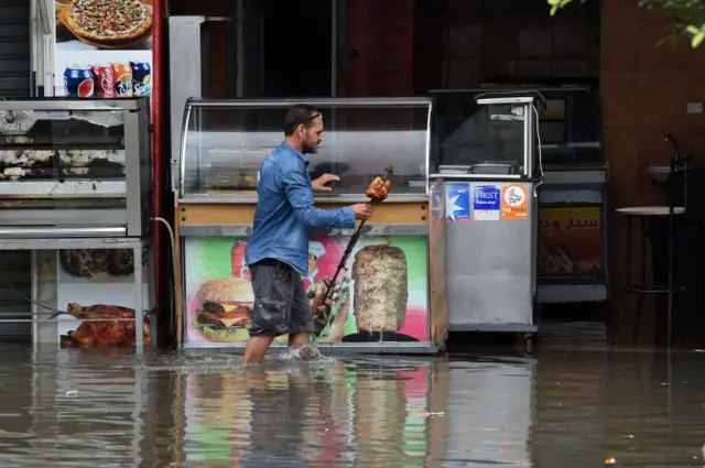 A shop owner tries to salvage his merchandise in a street flooded by torrential rains in the Tunisian capital Tunis on October 18, 2018