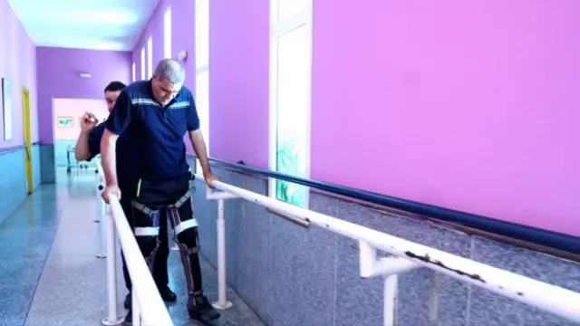 A man wearing braces on his legs takes part in guided exercise