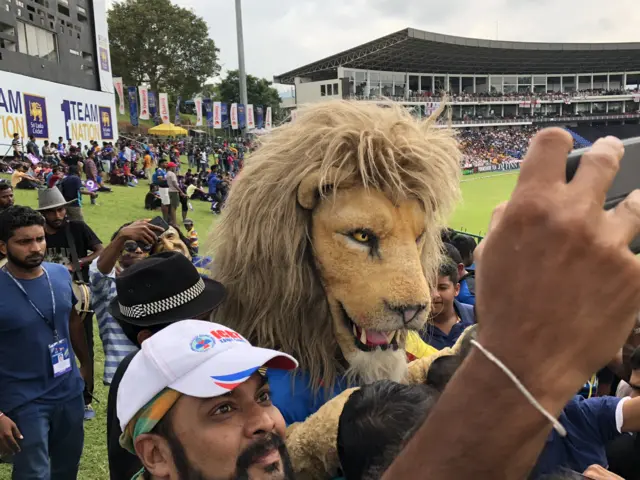 A Sri Lanka fan takes a selfie with a lion mascot in Pallekele