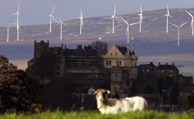 Castle, with sheep in the foreground and a windfarm behind