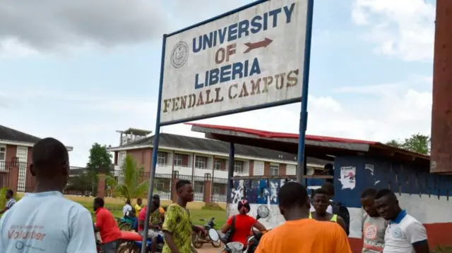 People stand outside the Fendall Campus of the University of Liberia near Monrovia, on October 12, 2017.