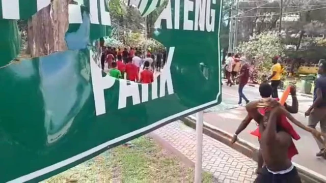 A student prepares to strike a sign with a blunt object