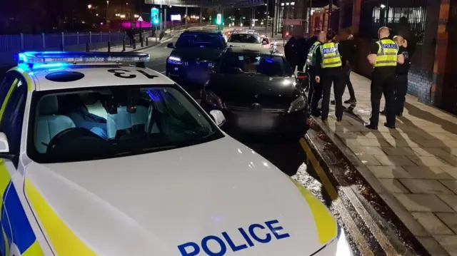 Police cars and a black Mercedes