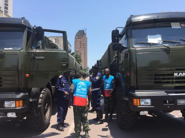 Election official talking to someone next to an army truck