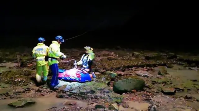 Rescuers winch a man out of the mud