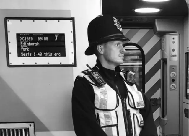 A police officer standing next to a train