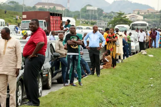 People standing on the roadside next to their cars