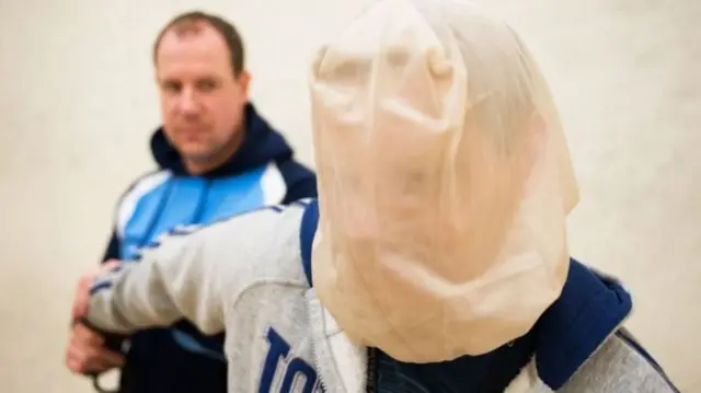 A man wearing a spit hood