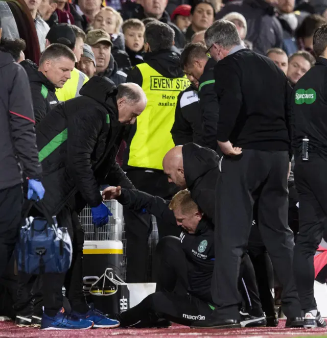 Neil Lennon is helped back to his feet after being hit by an object thrown from the main stand