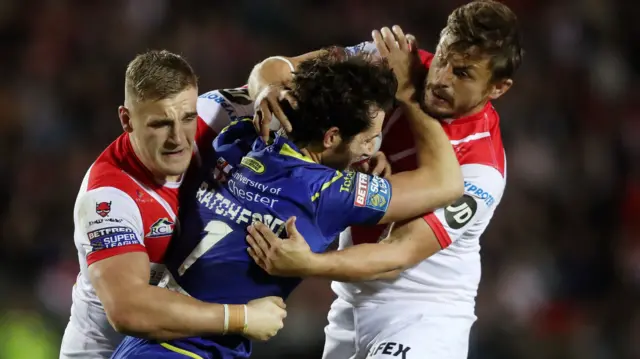 Stefan Ratchford of Warrington Wolves is tackled by Matty Lees and Jon Wilkin of St Helens