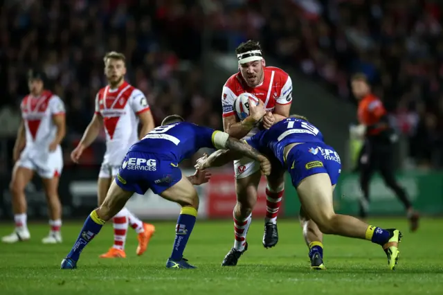 Luke Douglas of St Helens crashes into Daryl Clark and George King of of Warrington