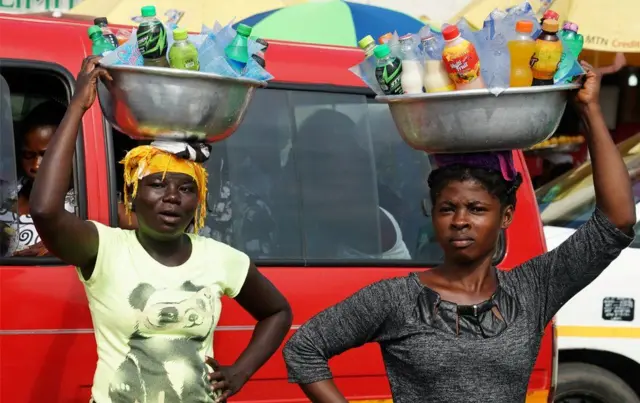 Two women holding bowls on their heads