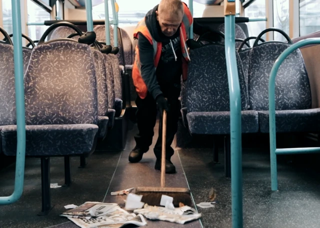 A man cleaning litter on a bus