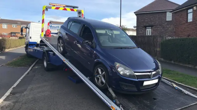 A car on the back of a recovery truck