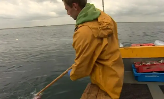 Fisherman picks plastic bottle from the water