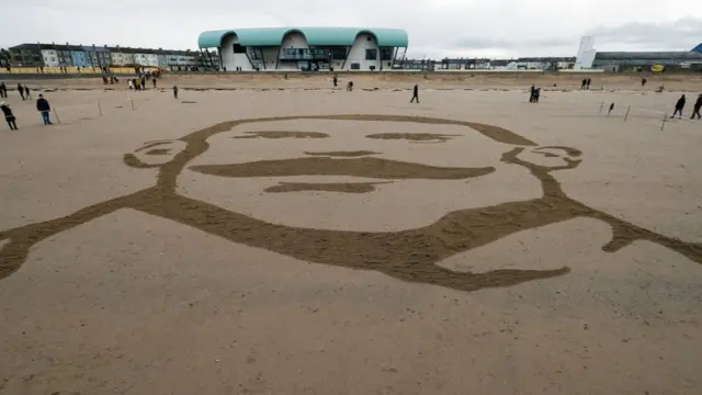 Volunteers gather on Redcar beach to take part in a large scale sand portrait project called Pages of the Sea