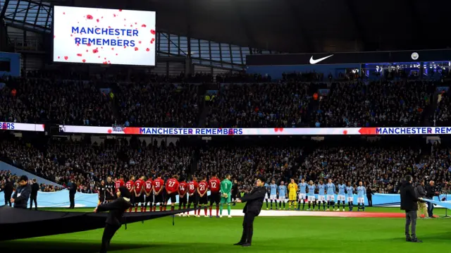Players, fans and officials observe a silence for Remembrance Day prior to the Premier League match between Manchester City and Manchester United