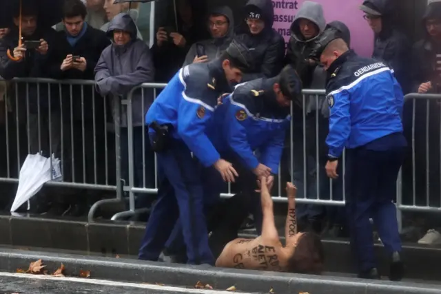 A topless protester is detained by French Police