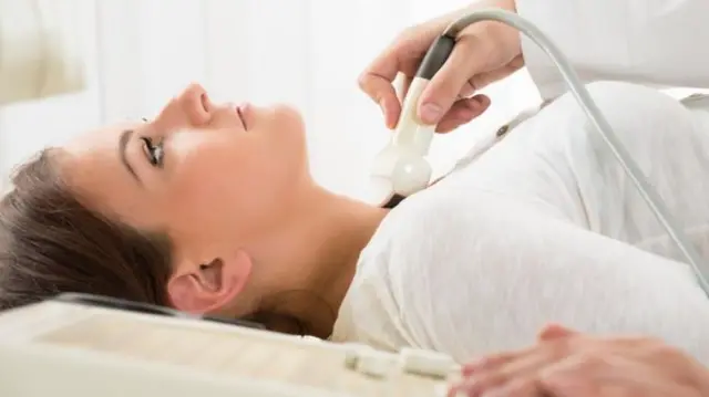 A woman having an ultrasound scan of her neck