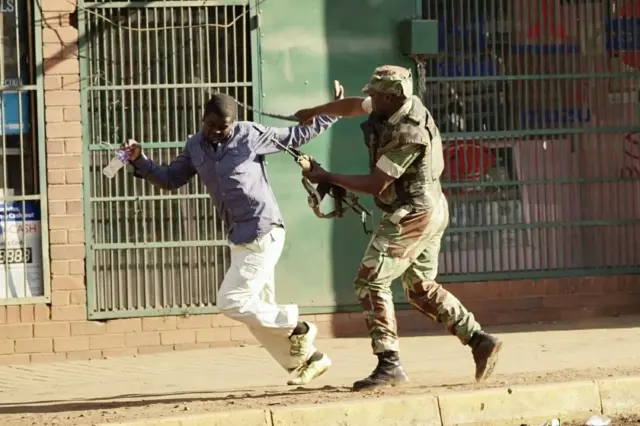 A Zimbabwean soldier beats a man in a street of Harare on August 1, 2018 as protests erupted over alleged fraud in the country's election