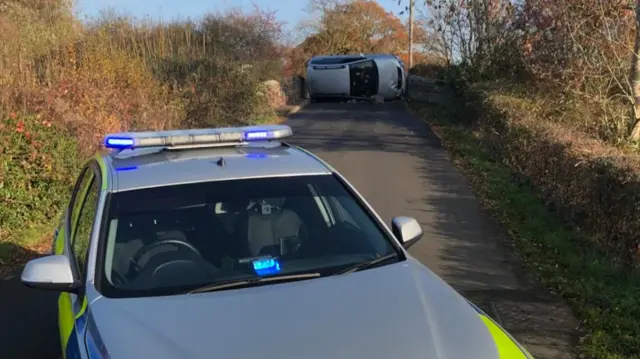 Car on its side on a country lane