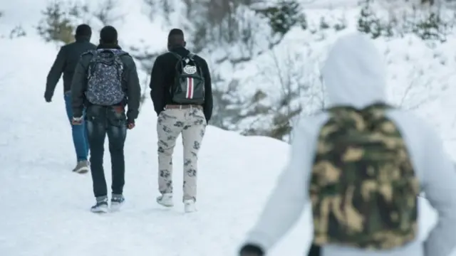 Migrants walk in the snow on a snow-covered pass to cross the border between Italy and France - January 2018