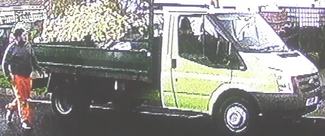 CCTV image of a man walking next to a white van