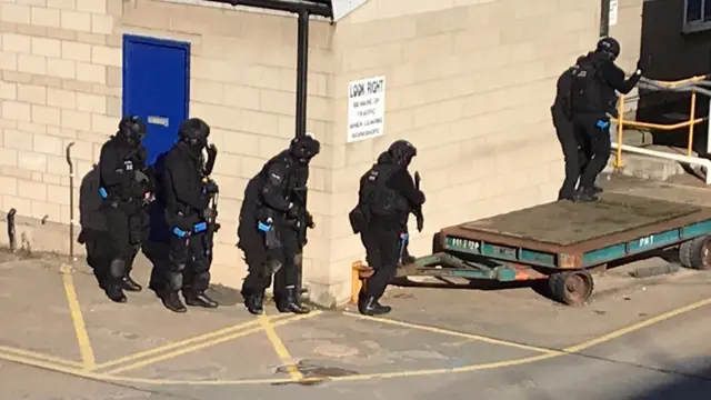 Officers shield themselves behind a wall