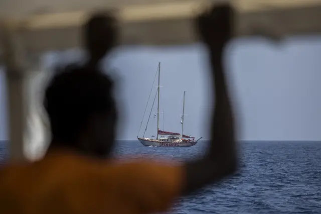 A migrant looks on as a charity rescue vessel patrols the Mediterranean