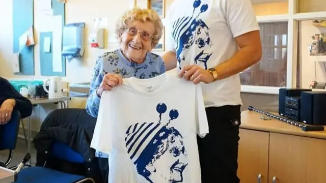 Jean Bishop holding a T-shirt with her face on it