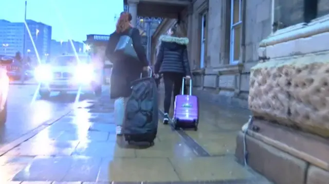 A pair of passengers pulling suitcases