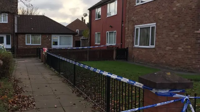 cordoned scene with flowers on gate