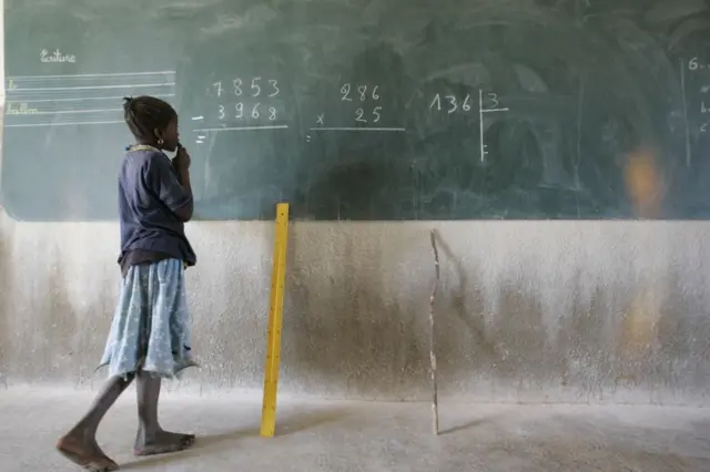 A child stood next to a blackboard at a school in Burkina Faso