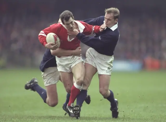 Former Wales scrum-half Rob Howley tries to escape a tackle from Scotland's Gregor Townsend in 1996